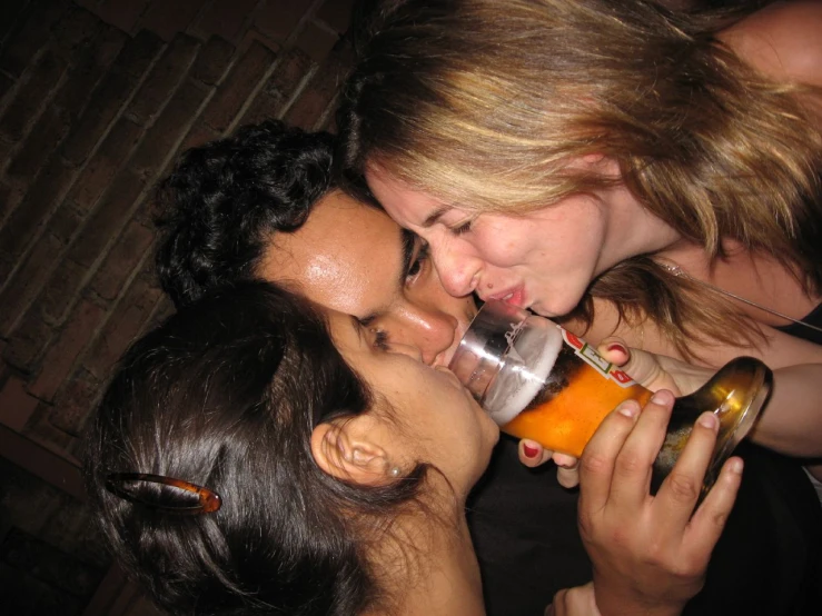 three friends share an affection and kiss while drinking beer