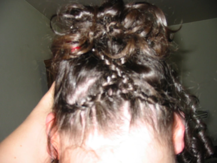 a woman with a messy bun is blow drying her hair