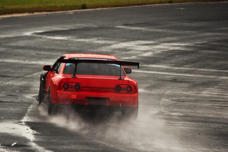 an orange race car racing down a paved road