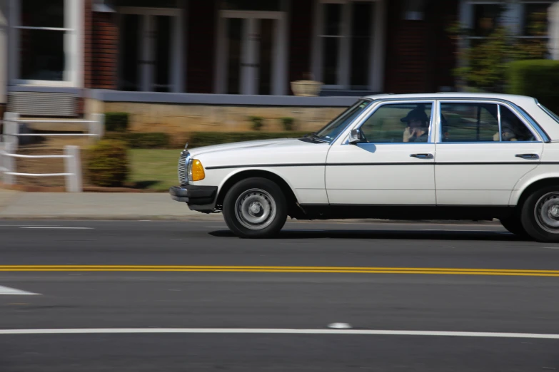 a white old fashioned car on the street in a city