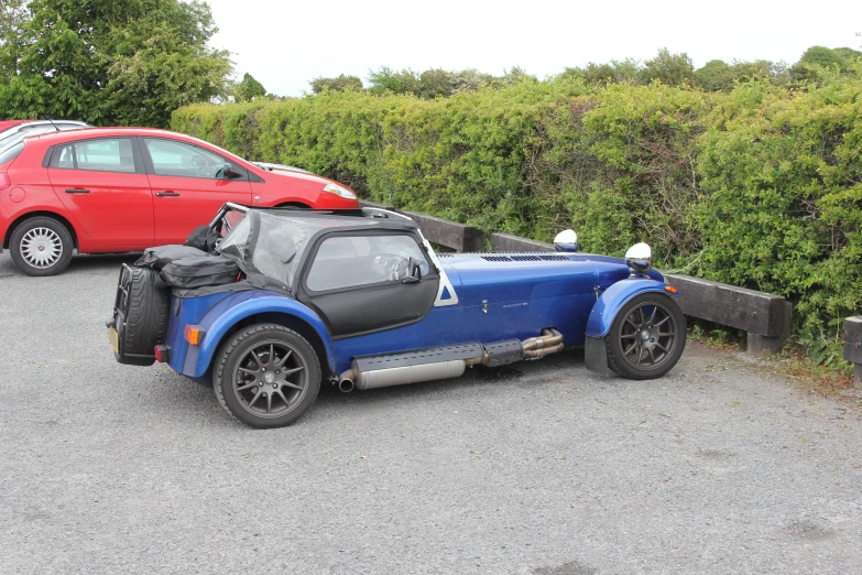 two cars are parked in front of a car with a trailer behind it