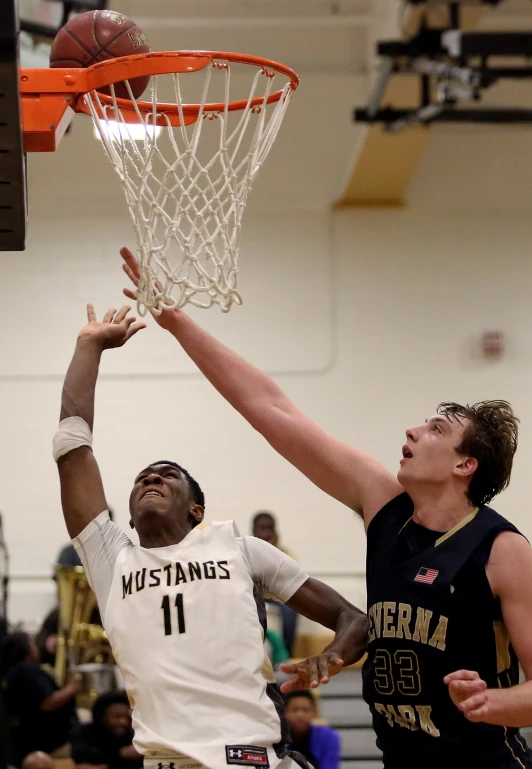 a man in a black and white uniform attempts to block the basketball