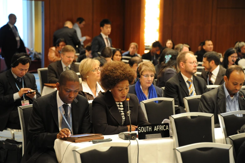 a group of business people sitting down listening to the speaker