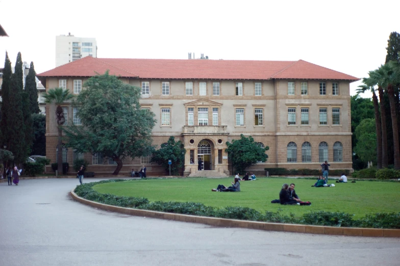 some people are on the grass outside of a large building