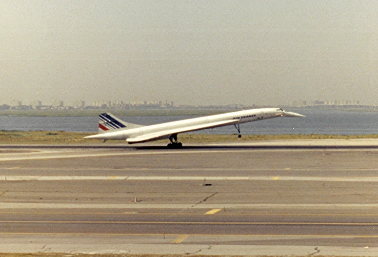 the plane is landing on the runway near water