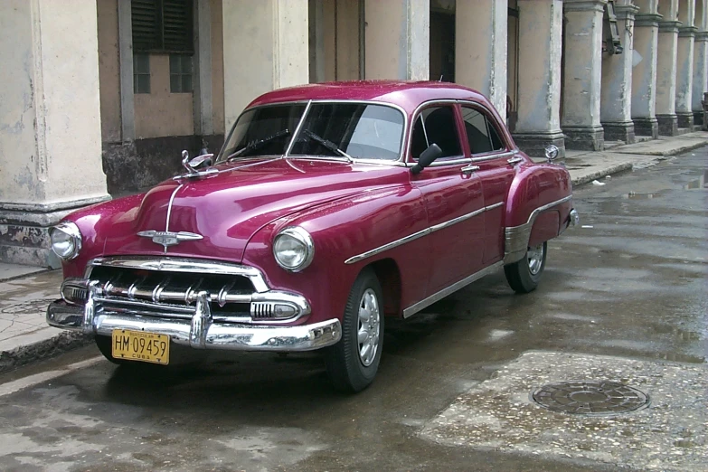 a car is parked on the side of the road in front of columns