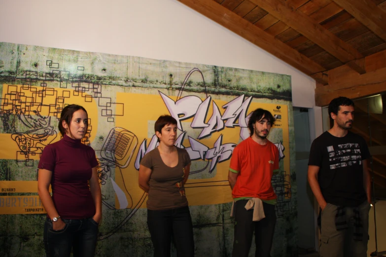 several people are standing in front of a graffiti wall