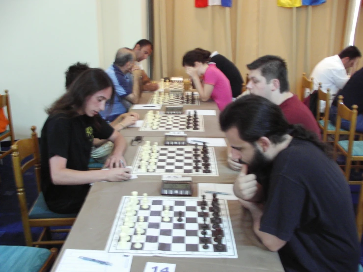 a group of people sitting around a table playing chess