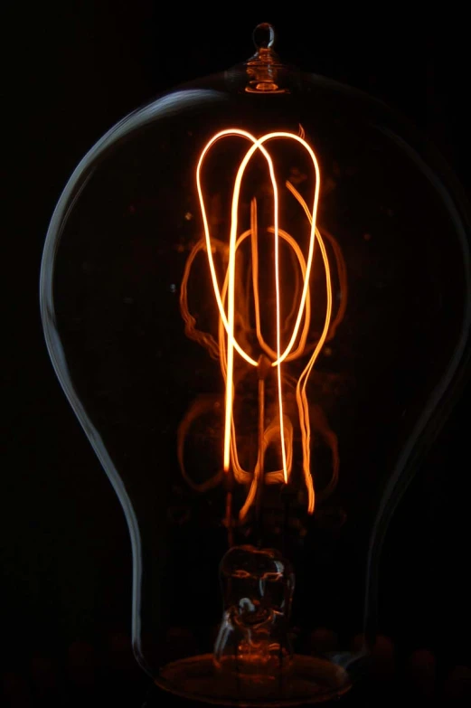 a lit light bulb that has some orange wire in it