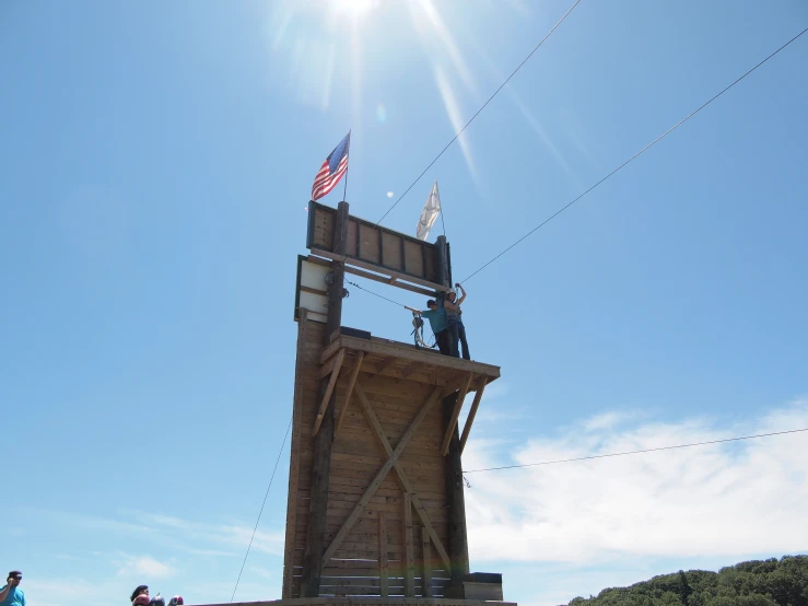 a man standing on top of a wooden tower with an american flag