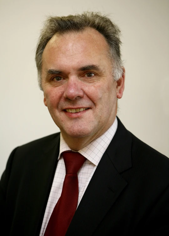 a smiling man with his hair combed in a suit