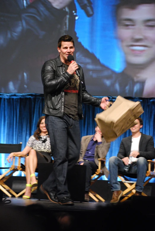 the man is holding a brown bag on stage