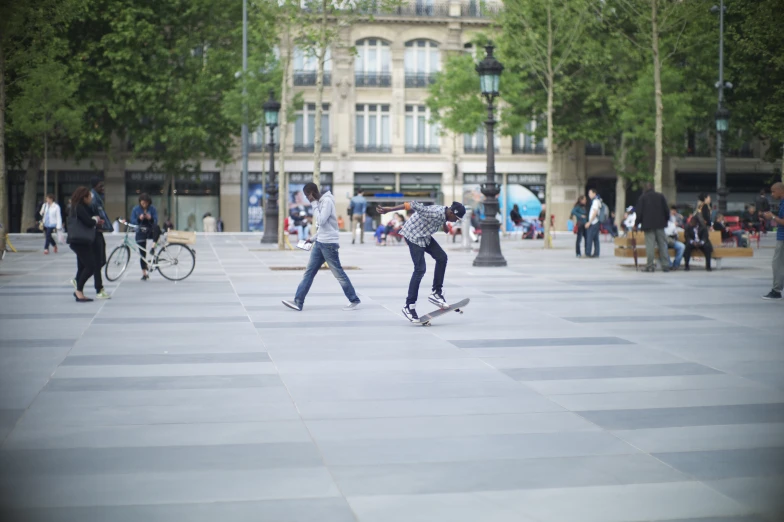 two skateboarders on a city street near buildings