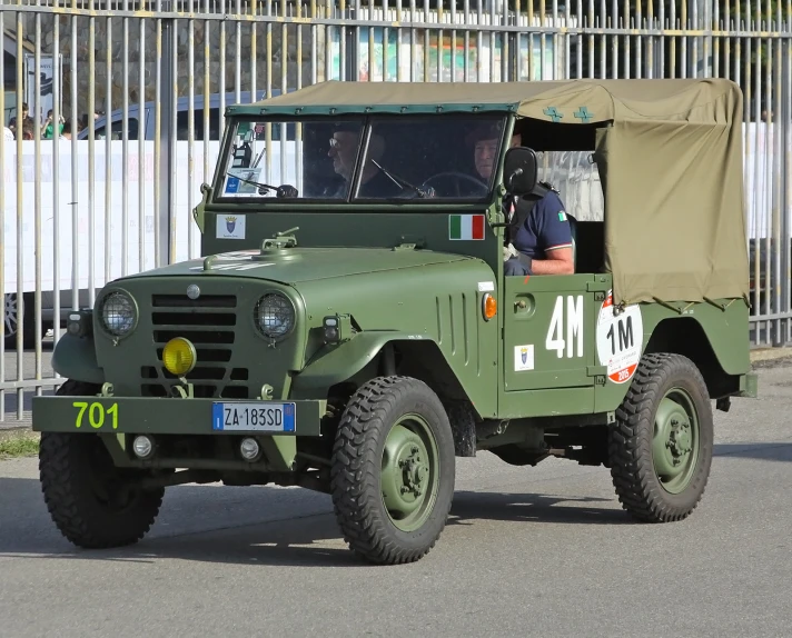 an army truck driving down a street next to a building