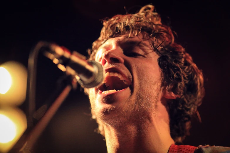 a man sings into a microphone while on stage