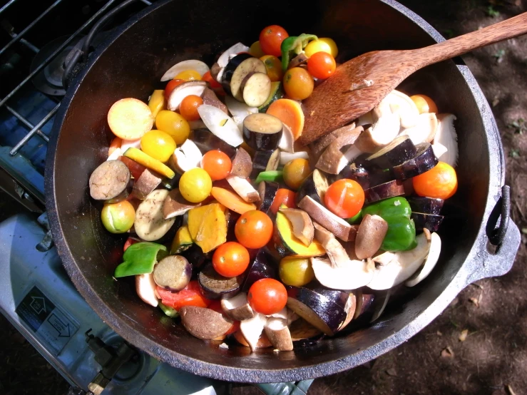 a pan with mushrooms, carrots and tomatoes cooking on a stove