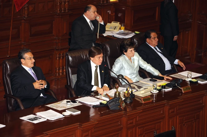 four men sitting at a table looking off into the distance