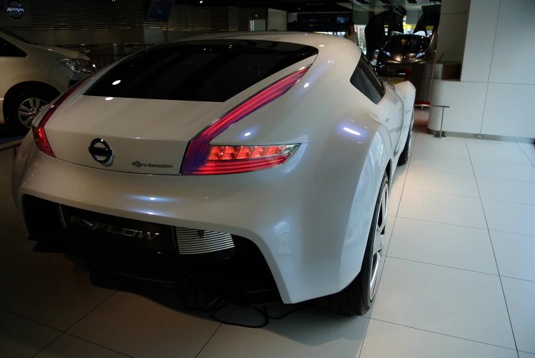 white sports car on display in show room with white tile flooring