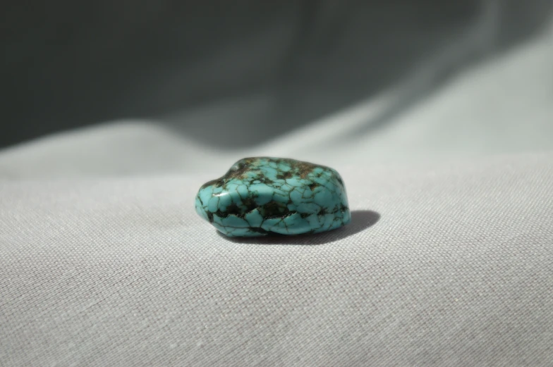 a green stone sitting on top of a white cloth