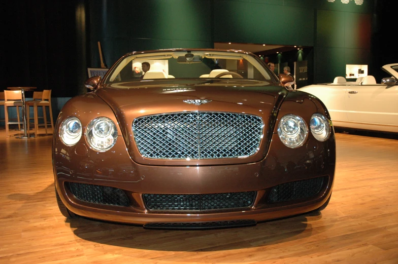 the front end of a brown bentley - continental at a museum