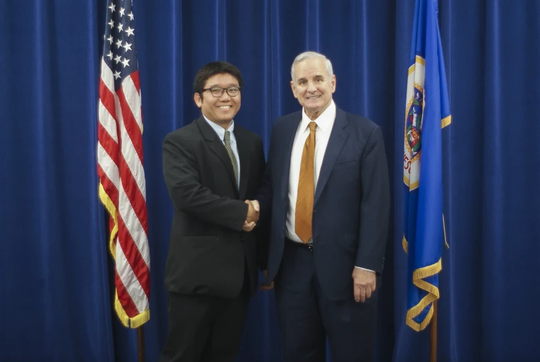 two men standing next to each other in front of flags