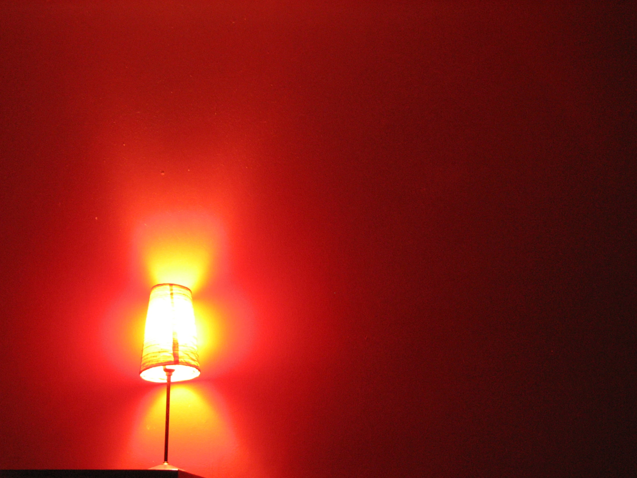 the lamp is bright yellow against a red wall