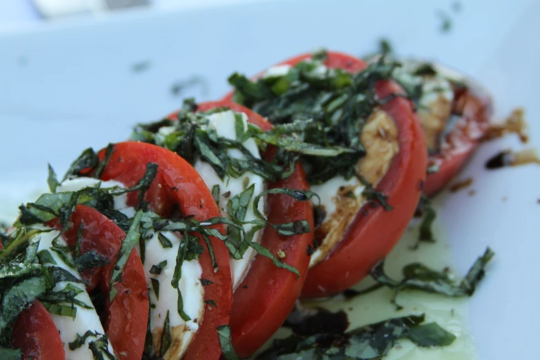 several sliced tomatoes and greens on a white plate