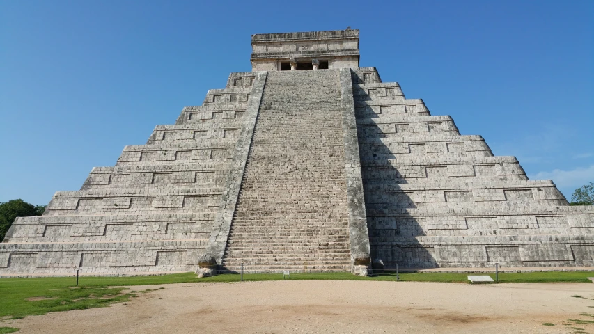 a tall pyramid on a grassy field with a blue sky