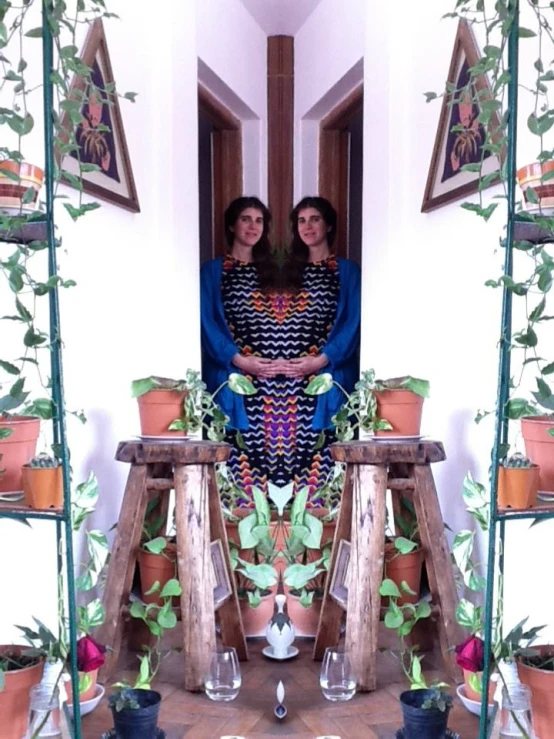 two women in front of a mirror on a table with some plants