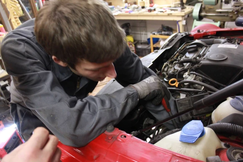 an auto mechanic working on a red car engine