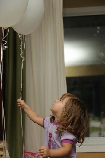 a girl is looking up at some balloons