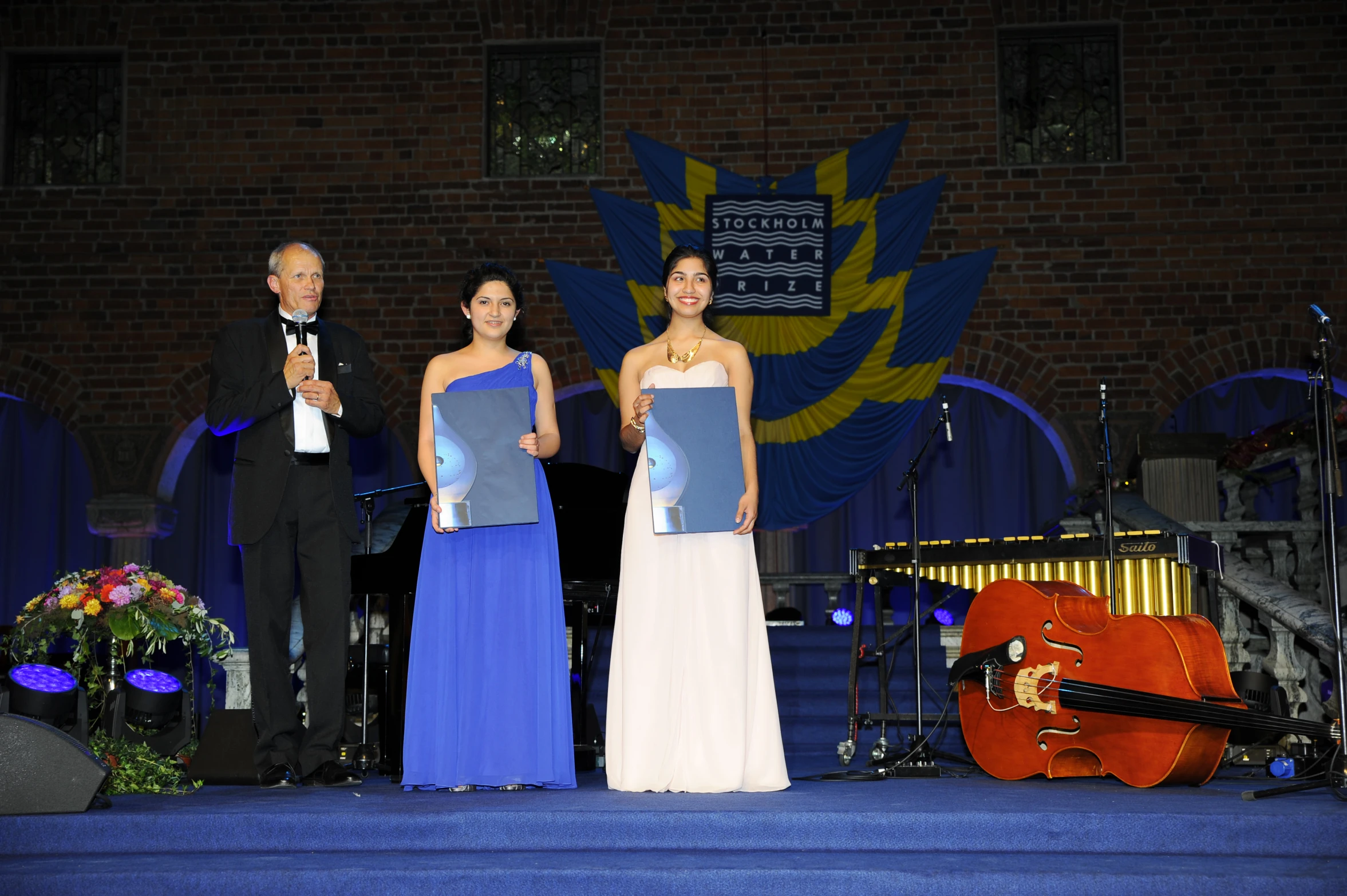 four people standing on stage next to an award