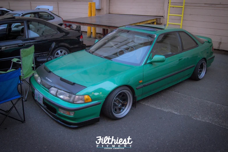 a very small green sports car sitting in a parking lot