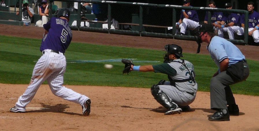 a baseball player hits the ball with his bat while the catcher holds out his glove