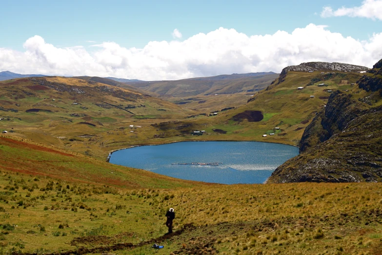 a person in the distance looking down at a lake