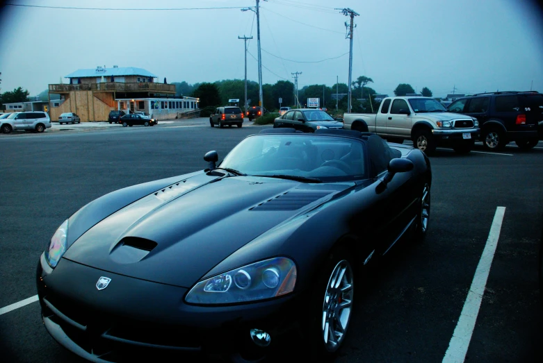 a sports car parked next to a truck in a parking lot