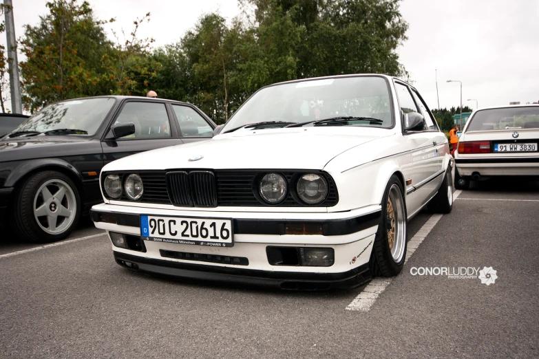 a white bmw parked in a lot next to other cars