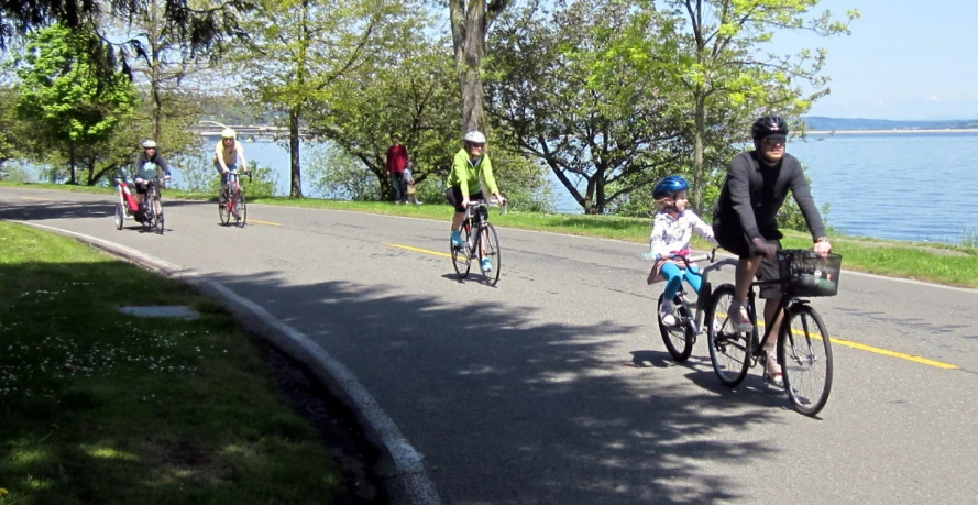 people riding their bikes on the water's edge