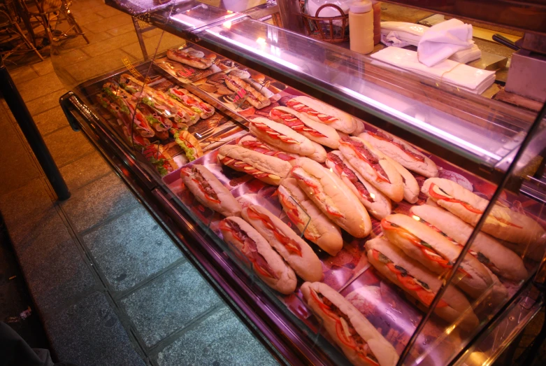 display case with many long  dogs and bread rolls