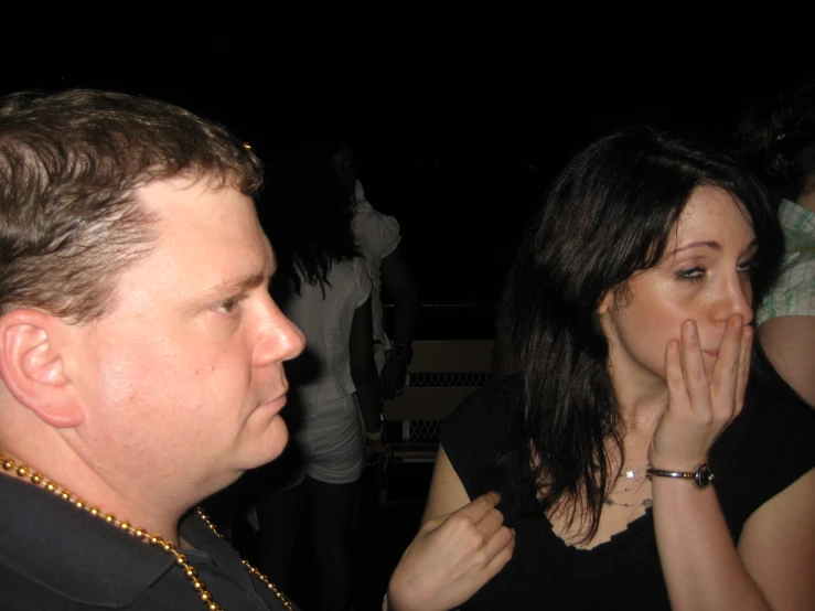 a woman talks on the phone near a man in a black shirt