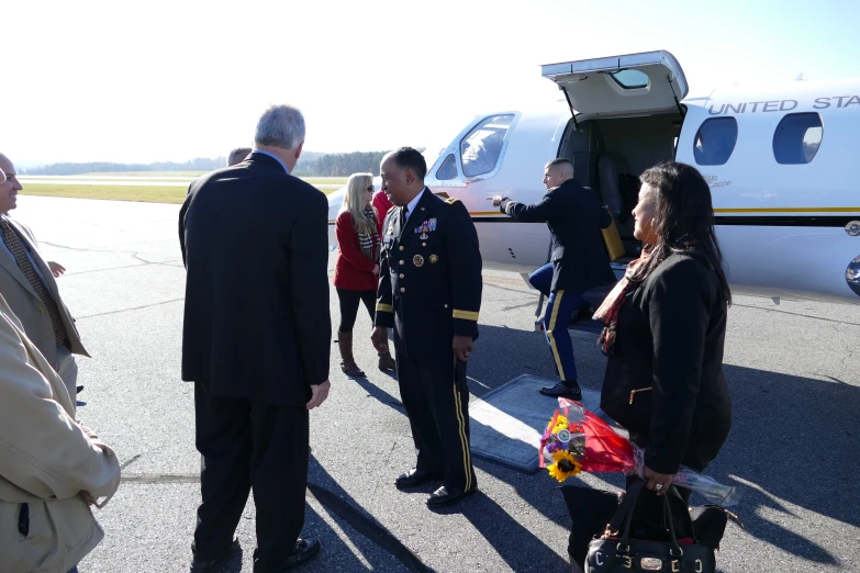 several people are standing on the tarmac in front of a small plane