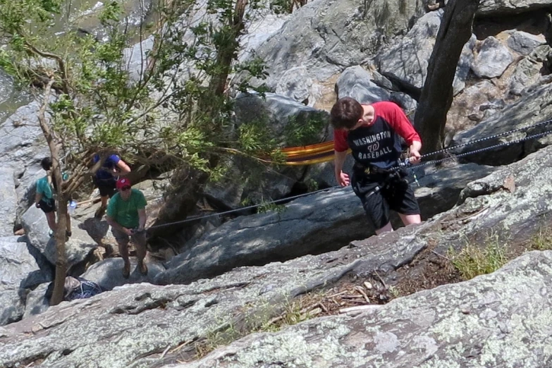 three people standing on the rocks in a forest