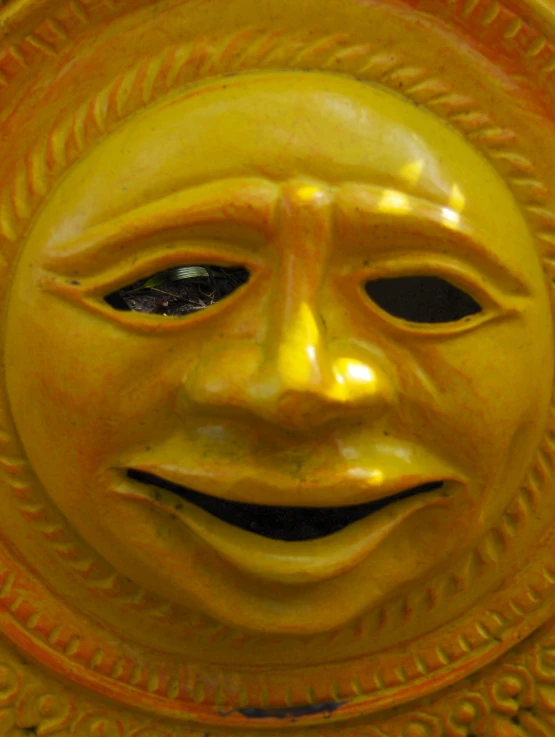 a yellow sculpture that has a smiling face on it