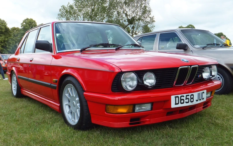 an old red bmw is parked in the grass
