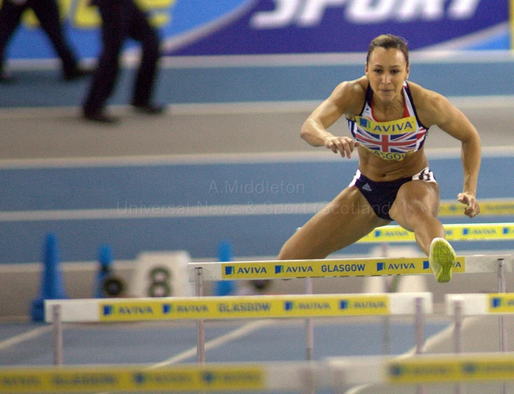 a female athlete jumping over a hurdle at a competition