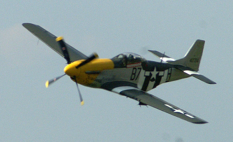 a small yellow black and white plane flying in the sky