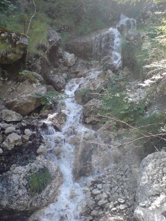 a stream of water running down a rocky hill side