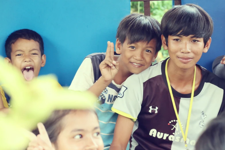 three boys show their peace signs while one girl stands with a little dog