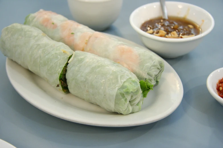 a plate filled with spring rolls and sauces on a table
