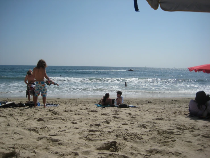 the family sits at the beach watching the surfers